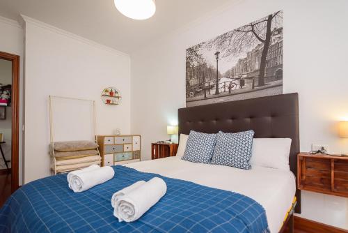 Un dormitorio con una cama azul y blanca con toallas. en O Faro Apartments, en Ribadeo