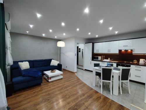 a living room with a blue couch and a kitchen at Apartament na Szewskiej in Głogów