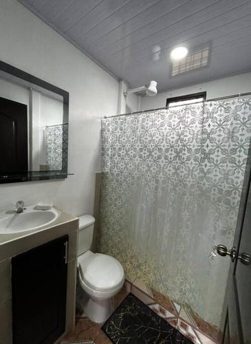 a bathroom with a toilet and a shower curtain at Casita de Campo in Sardinal