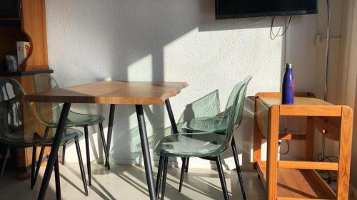 a table with green chairs and a table with a vase on it at Belle vue sur la mer et les Pyrénées in Le Barcarès