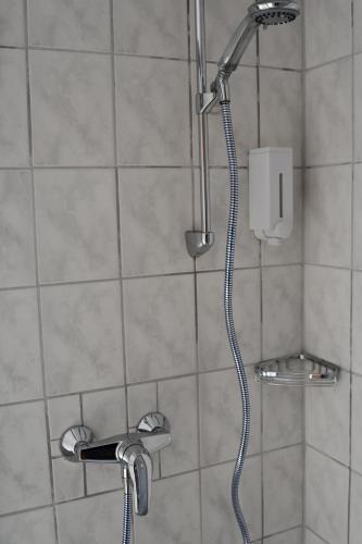 a shower with a shower head in a bathroom at Garni Hotel-Pension Holum in Neuharlingersiel