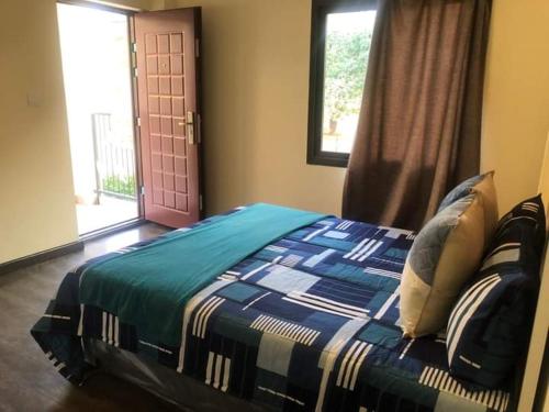 a bedroom with a bed and a window and a door at LouieVille Apartments in Lusaka