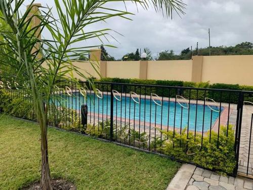 a black fence next to a swimming pool at LouieVille Apartments in Lusaka