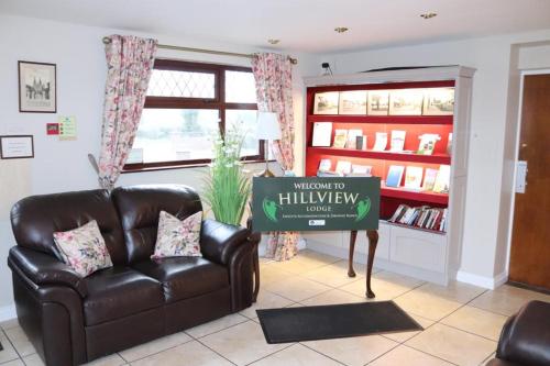 a living room with a brown leather couch and a sign at Hillview Lodge in Armagh