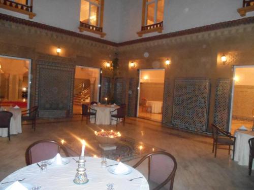 a dining room with white tables and chairs and candles at Dar Nador in Nador