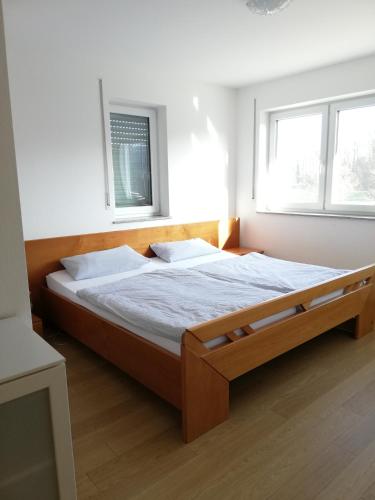 a bed in a room with two windows at Ferienwohnungen Weishaupt in Meckenbeuren