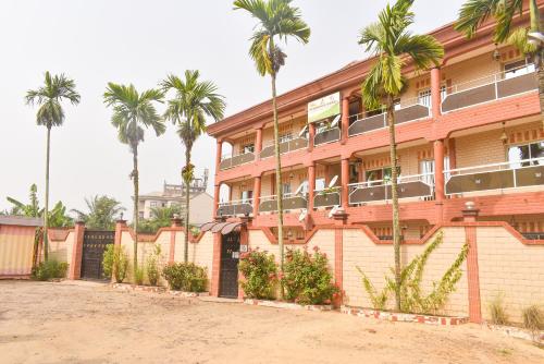 a building with palm trees in front of it at Résidence Hotelière Borel Denver in Douala