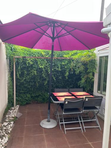 una sombrilla morada sobre una mesa y sillas en un patio en Belle maison, en Vigneux-sur-Seine