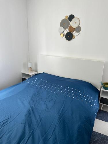 1 dormitorio con 1 cama azul y reloj en la pared en Belle maison, en Vigneux-sur-Seine
