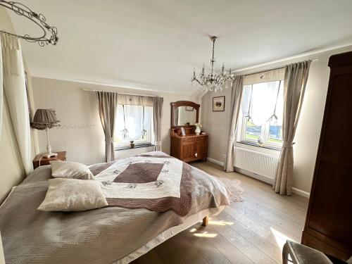 a bedroom with a large bed and two windows at Maison Durbuy L'air du temps in Weris