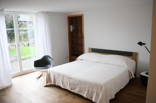 um quarto com uma cama, uma cadeira e uma janela em Bed & Breakfast Gaetzi em Windlach
