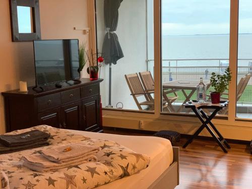 1 dormitorio con cama y vistas al océano en Studio mit Meerblick und großer Loggia - Direktzugang zur Nordsee, en Wilhelmshaven