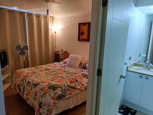 a bedroom with a bed with a flowered blanket and a sink at Apartamento en las alturas, santiago! in Santiago
