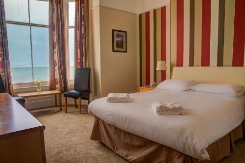 Chatsworth House Hotel في خلنددنو: غرفة فندق عليها سرير وفوط
