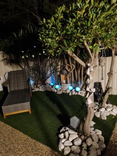 un jardin avec un arbre, un banc et des lumières dans l'établissement Torreilles plage: villa atypique bord de mer méditerranée, à Torreilles