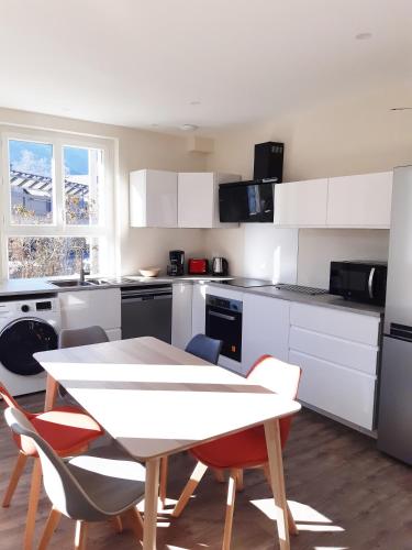 une cuisine avec des armoires blanches et une table et des chaises dans l'établissement T3 neuf 65m2 5 personnes avec jardin au calme, ménage inclus, local vélo, à Luchon