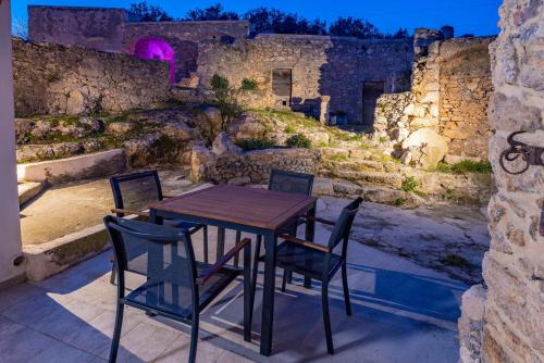 uma mesa e cadeiras num pátio com uma parede de pedra em Casa Vacanze Arma delle Manie em Finale Ligure