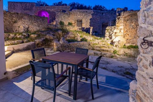 stół i krzesła na patio z kamienną ścianą w obiekcie Casa Vacanze Arma delle Manie w mieście Finale Ligure
