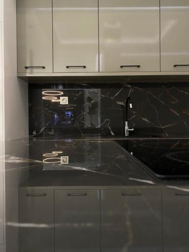 a kitchen with black marble counter tops and white cabinets at DoorMat#6 Domus Dei in Thessaloniki