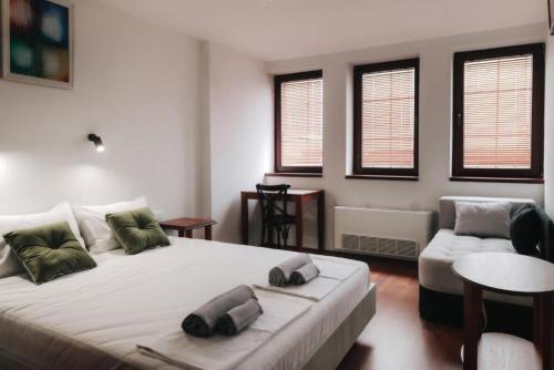 a bedroom with a bed and a couch and windows at Hotel Castrum in Skopje