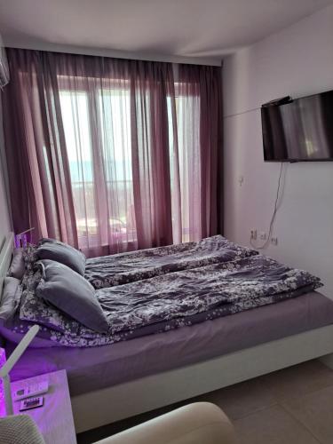 ein Schlafzimmer mit einem Bett mit violetter Bettwäsche und einem Fenster in der Unterkunft Stensi Atlantis studia in Rawda