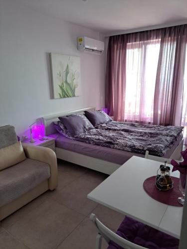 a bedroom with a bed and a couch and a window at Stensi Atlantis studia in Ravda