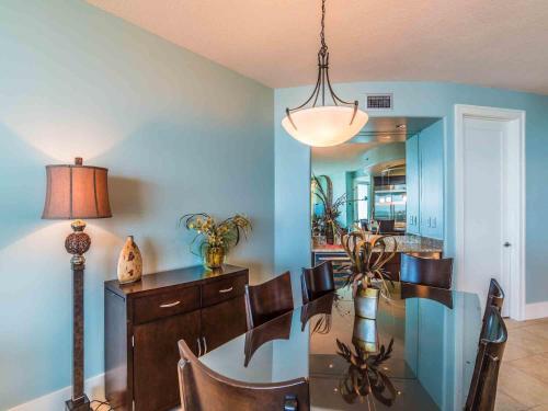 a dining room with a table and chairs and a lamp at Bella Luna #404 in Orange Beach