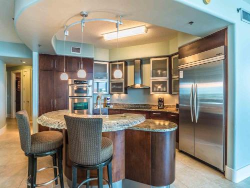 a kitchen with a large island with bar stools at Bella Luna #404 in Orange Beach