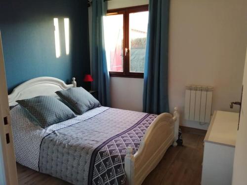 a bedroom with a bed with blue walls and a window at La framboisette in Le Vaudreuil