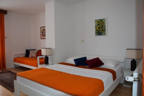 1 dormitorio con 2 camas de color naranja y blanco en Apartments Crobeg, en Rab