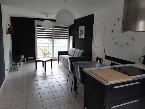 a kitchen and living room with a couch and a table at L'appartement du parc vert marine in Houlgate