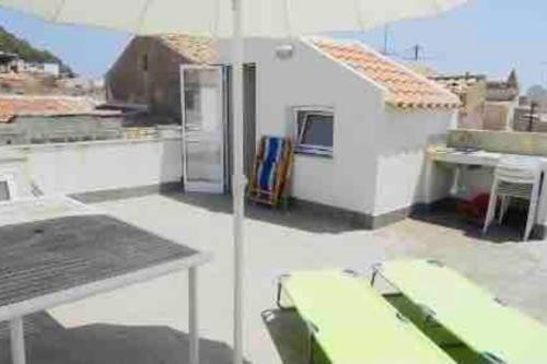 ein weißes Gebäude mit einem Tisch und einem Regenschirm in der Unterkunft Casa Gigé in Ustica