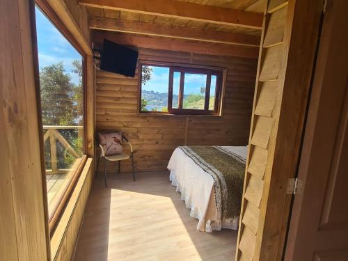 a bedroom in a log cabin with a bed and a window at Turismo del Bosque in Castro
