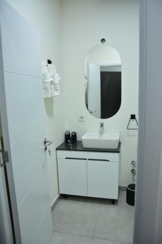 a white bathroom with a sink and a mirror at Magnolija Apartments in Bitola