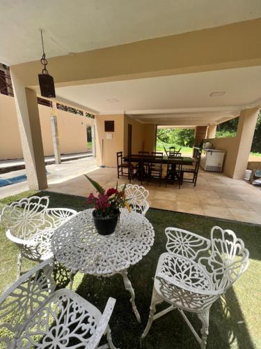 eine Terrasse mit weißen Tischen und Stühlen sowie einem Tisch mit Blumen in der Unterkunft Chale Ouro Verde - Serra de Guaramiranga in Baturité