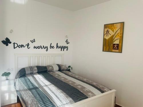 un dormitorio con una cama con las palabras no te preocupes se feliz en Pintadera´s house/Tara en Icod de los Vinos