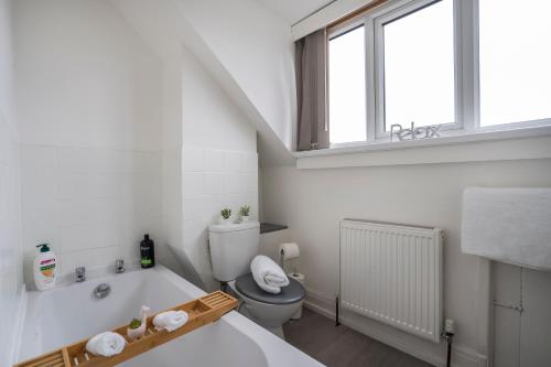 a white bathroom with a toilet and a bath tub at Quiet Neighborhood-Free Parking in Blackpool