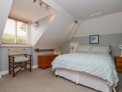 a bedroom with a bed and a chair and a window at The Watch in Porthcurno