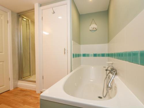 uma banheira branca na casa de banho com um chuveiro em The Watch em Porthcurno