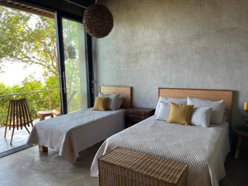 Tamanique的住宿－One of a kind countryside home，一间带两张床的卧室和一个阳台