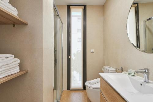 een badkamer met een toilet, een wastafel en een spiegel bij Elite Beach in Málaga