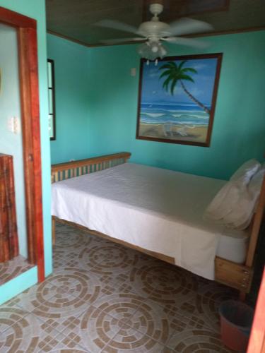 1 dormitorio con 1 cama en una pared azul en Hospedaje Rosa Del Mar, en Isla Grande del Maíz