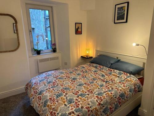 a bedroom with a bed with a colorful comforter and a window at Cosy authentic flat in the heart of Galashiels in Galashiels