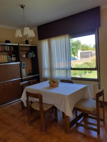 comedor con mesa, sillas y ventana en Casa con vistas a 100 metros de una playa en Panxón, en Nigrán