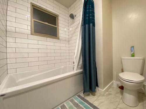 a bathroom with a white tub and a toilet and a window at Charming Brick Home with bonus space & foosball in Spokane