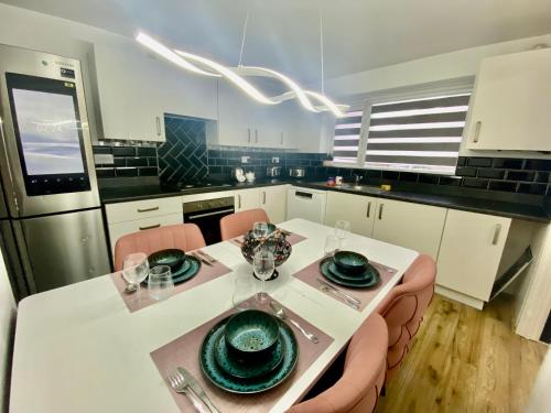 a kitchen with a white table with green dishes on it at 3 Bedrooms House in Manchester in Manchester