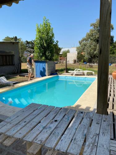 un hombre de pie junto a una piscina azul en Quinta en Villa Constitución