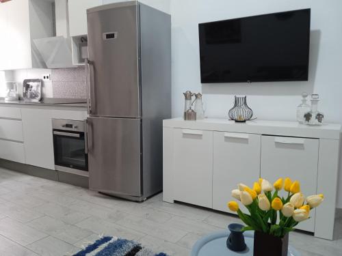 a kitchen with a refrigerator and a vase of yellow flowers at Apartamentos Lax in Almería