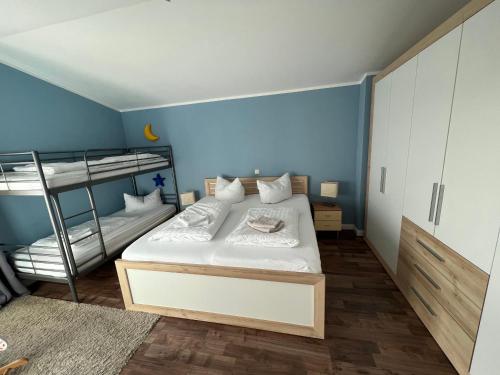 a bedroom with two bunk beds and a blue wall at Meerblick Apartments Villa Vineta Göhren in Göhren