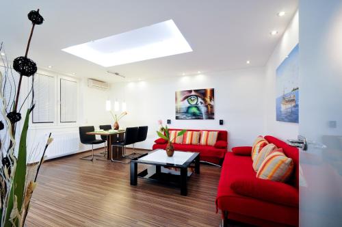 salon z czerwoną kanapą i stołem w obiekcie Apartment Giuliano Vienna w Wiedniu